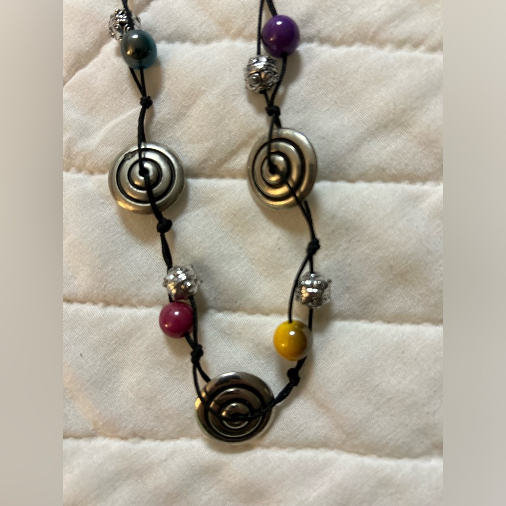 Necklace with lots of colors and cotton cord and metal clasp.